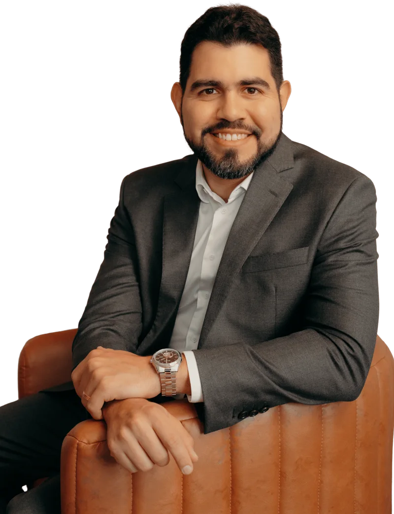Dr. Thiago Mourão sentado em poltrona, de terno